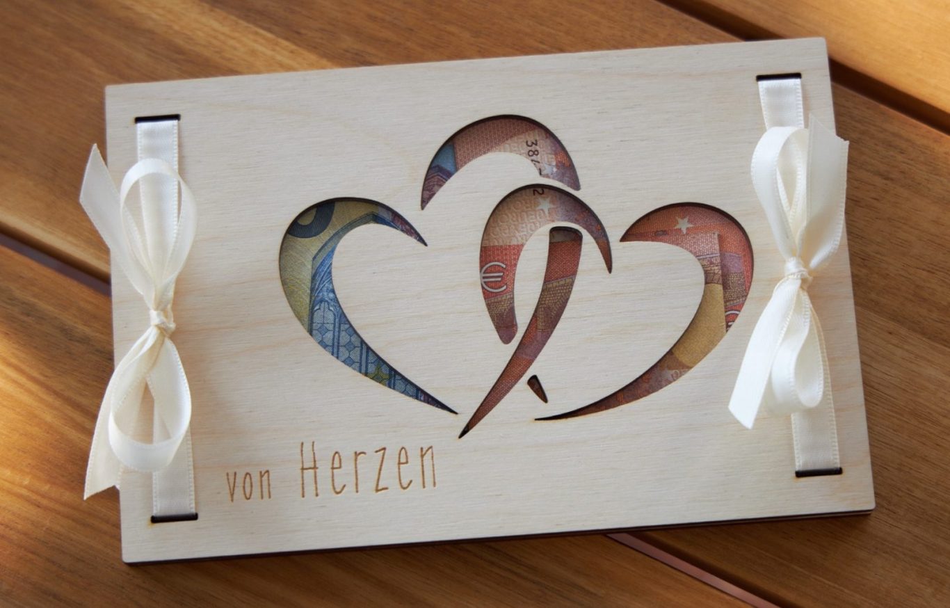 Holz Geschenkkarte zum verpacken von Geldscheinen mit einer Gravur von Herzen und ausgeschnittenen Herzen.